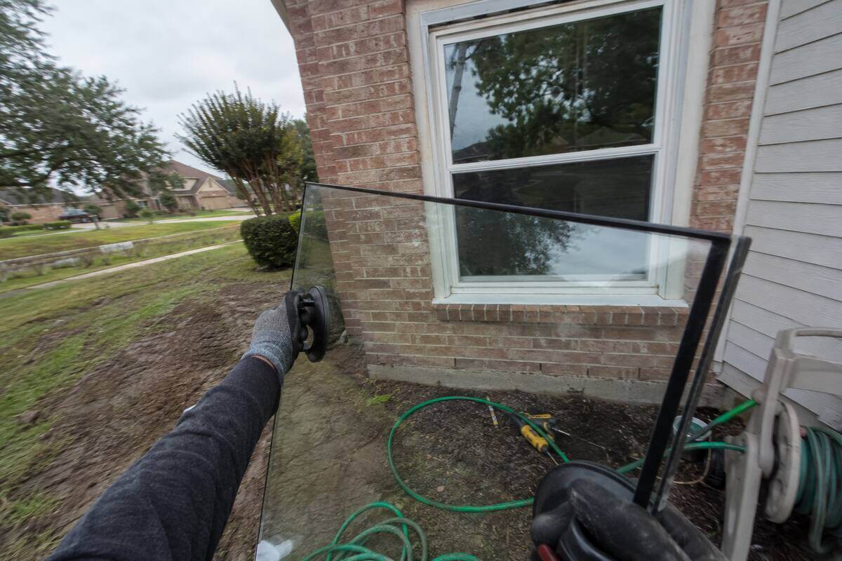 Sealed glass unit carried on suction handles toward a window opening